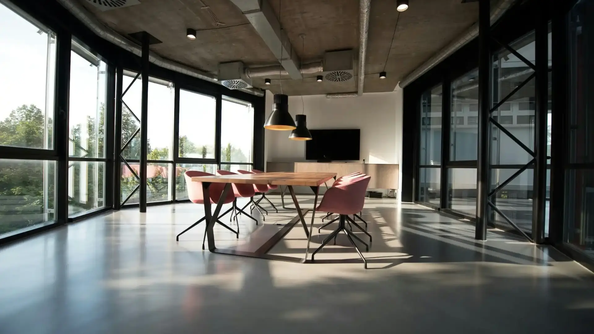 Sala de juntas corporativa con mesa de madera, sillas rosas y ventanales de piso a techo: contabilidad para personas morales de Rodríguez Bravo y Asociados, con contabilidad electrónica, estados financieros mensuales y estrategia fiscal.